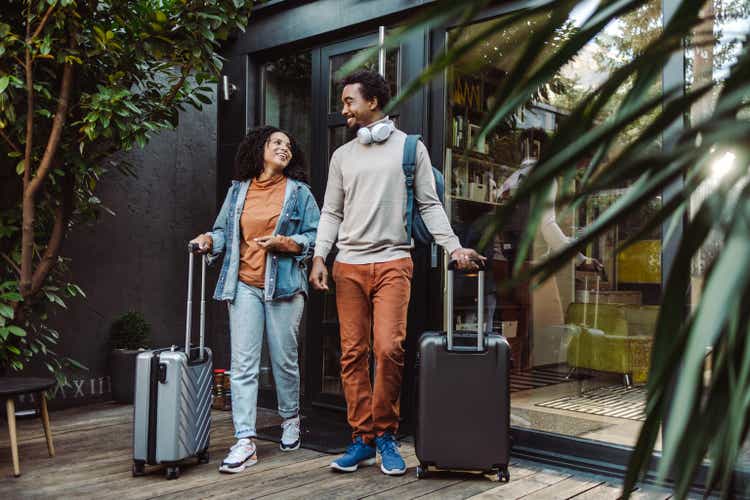 Turistas afroamericanos con maletas frente al apartamento alquilado