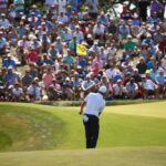 Man stands on golf course in front of crowd