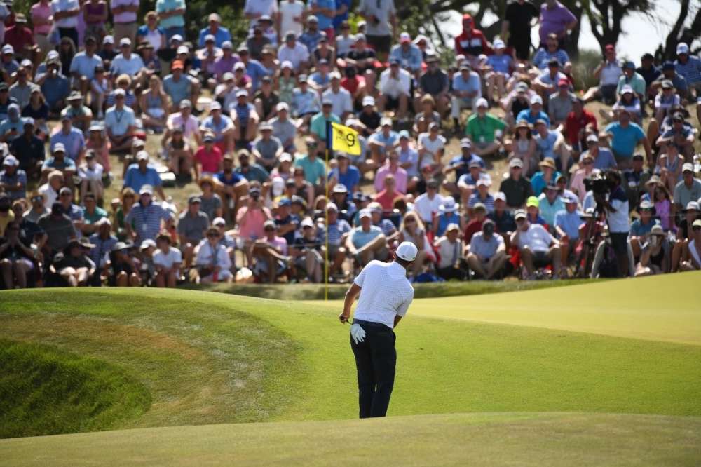 Man stands on golf course in front of crowd