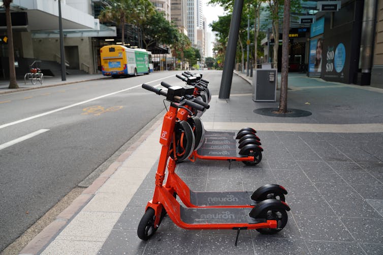 Los scooters eléctricos están estacionados al costado de la carretera de la ciudad.
