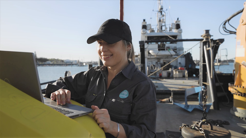 Un científico de CSIRO en un barco revisando datos sobre la calidad del agua en una computadora portátil.