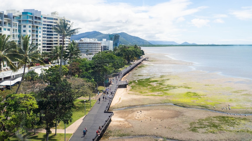 An aerial image of the promenade along the Cairns esplanade with tall buildings, mud flats and the sea on either side.