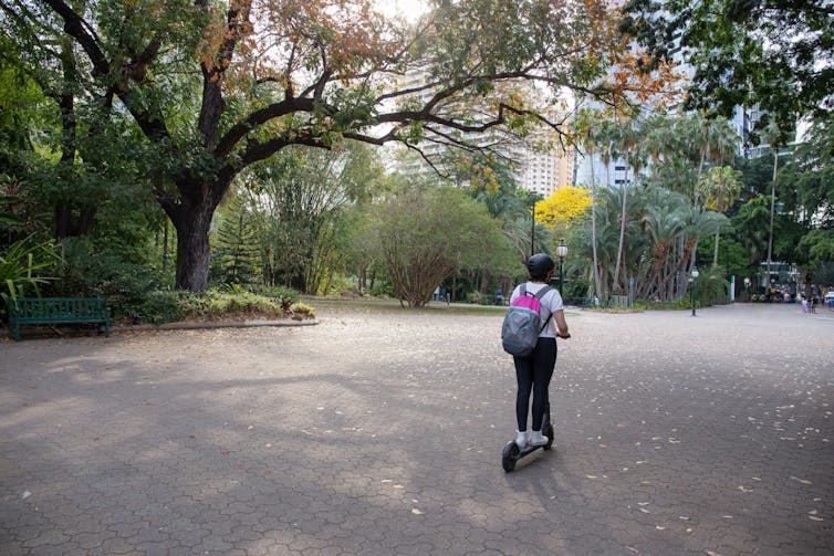 Un hombre conduce una scooter eléctrica por el jardín botánico.