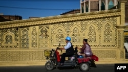 ARCHIVO - Esta foto tomada el 16 de julio de 2023 muestra a uigures montando triciclos en la ciudad de Kashgar, en la región de Xinjiang, en el noroeste de China.