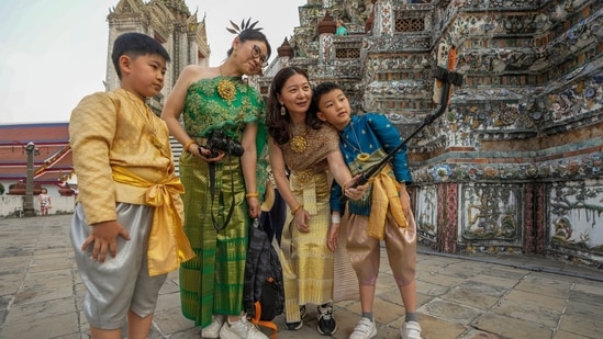Turistas familiares chinos alquilan trajes tradicionales tailandeses y se toman selfies en Wat Arun. 