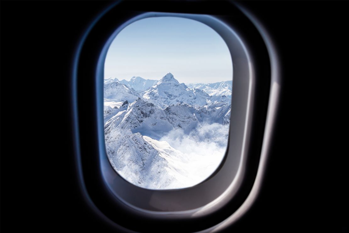 Una imagen de una montaña cubierta de nieve desde la ventana de un avión.
