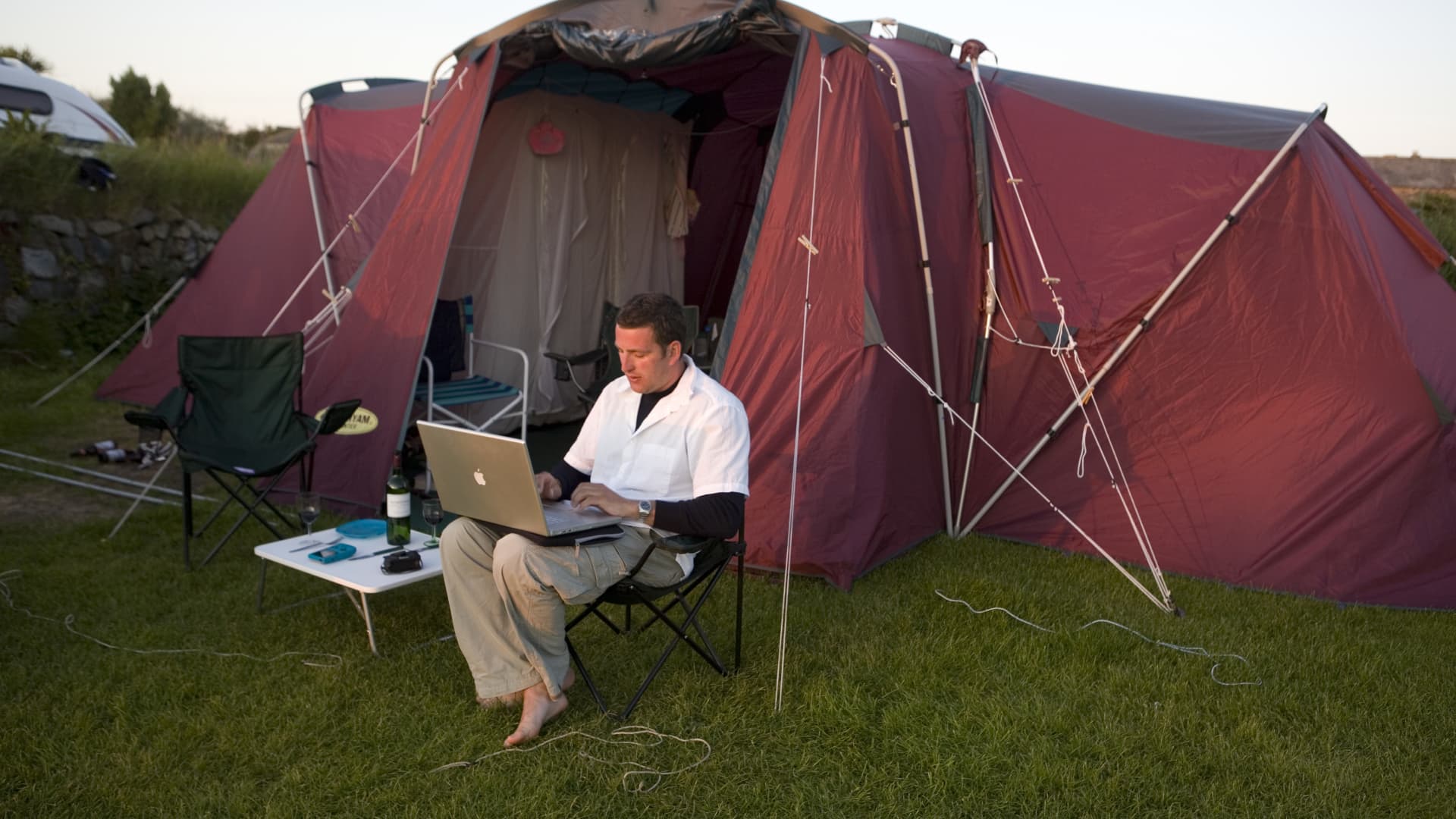 Un campista se toma un tiempo para trabajar en su computadora portátil durante unas vacaciones familiares en un campamento.