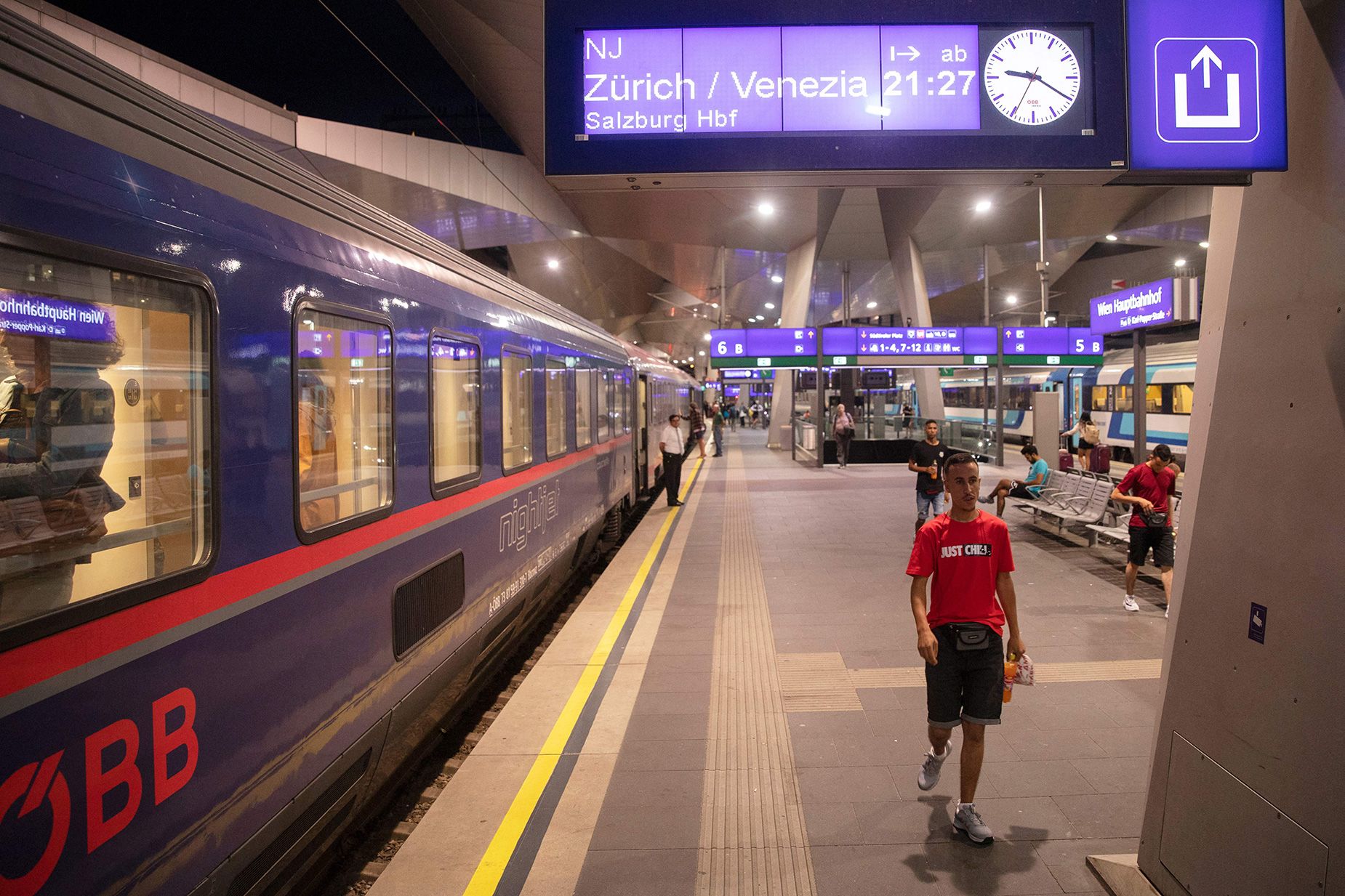 Se ven pasajeros en el andén frente a la línea de tren nocturno Viena-Venecia (-Zurich) de los Ferrocarriles Federales de Austria.  Los trenes nocturnos están regresando a Europa gracias a su baja huella de carbono.