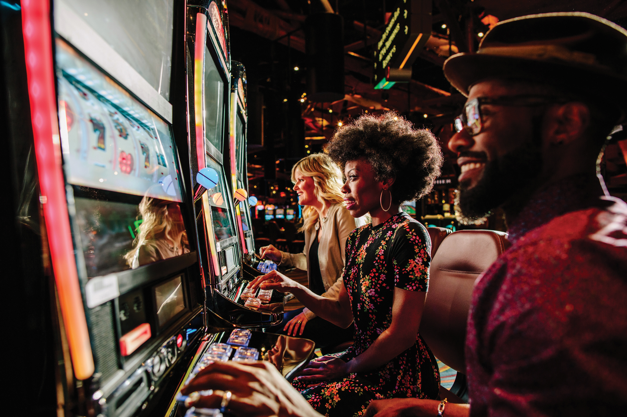 Una imagen de tres personas jugando a las tragamonedas en un casino.