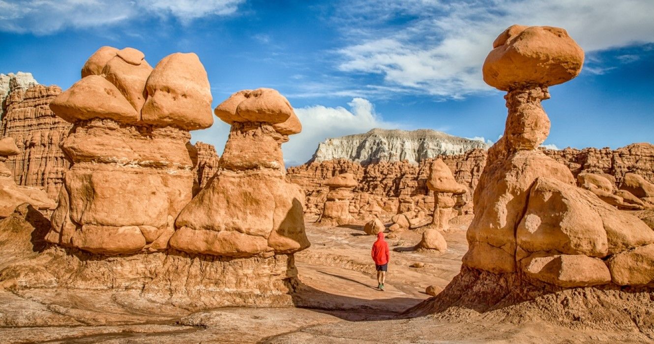 Vista de un hombre caminando entre las espectaculares formaciones de arenisca Hoodoos en el famoso Parque Estatal Goblin Valley, Utah.