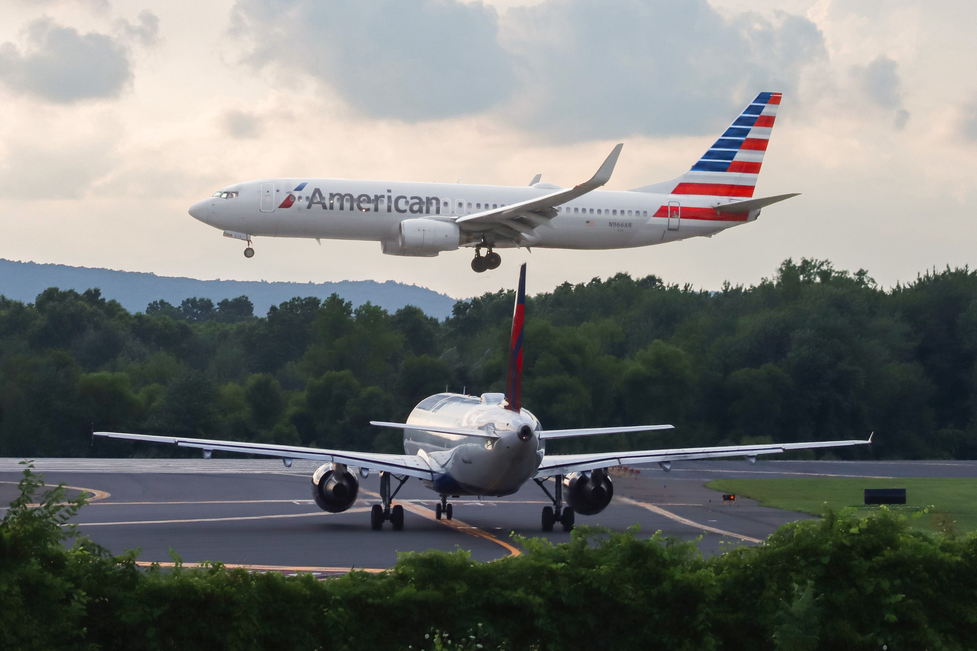 Un Boeing 737 de American Airlines aterriza mientras un avión de Delta Airlines espera en la plataforma.