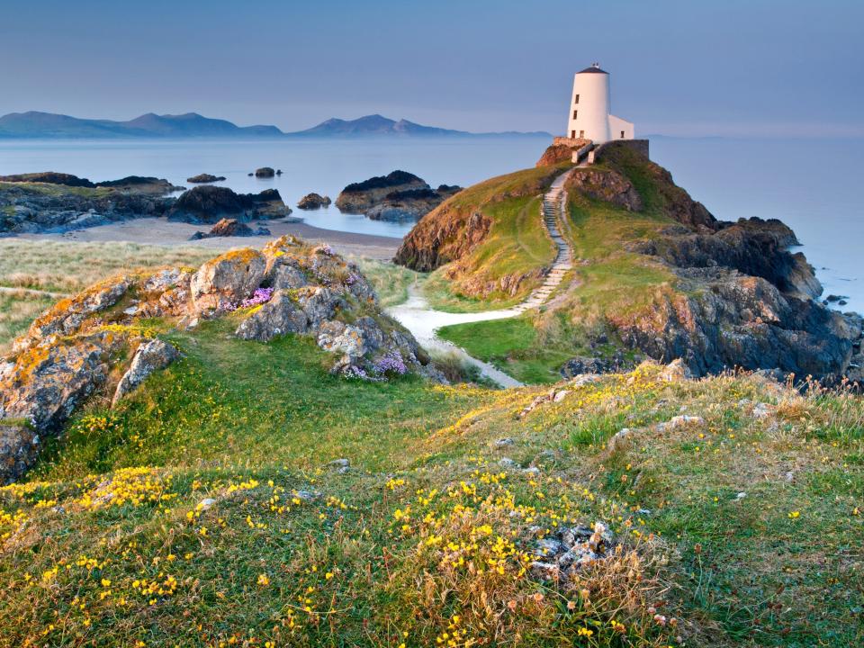 Un faro en el borde de la isla Llanddwyn con las montañas de la península de Lleyn al fondo