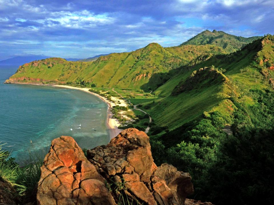 Una vista de la playa a las verdes montañas alrededor de Fatukama Cristo Rey Deli en Timor-Leste