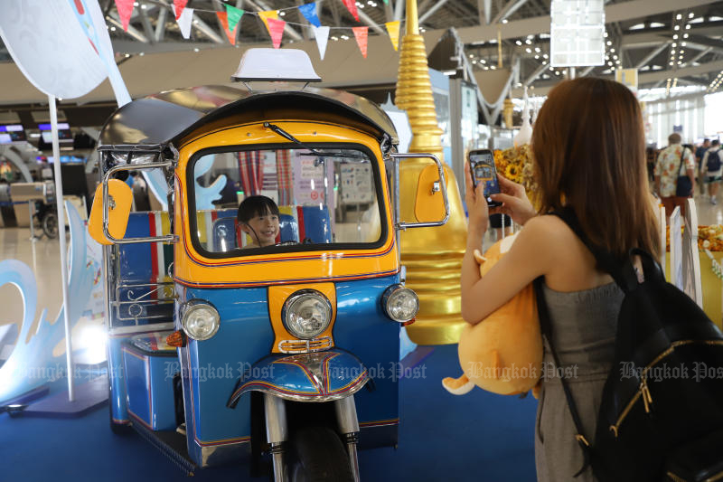 Un joven turista toma una fotografía de un tuk-tuk expuesto en el aeropuerto de Suvarnabhumi.  (Foto: Worth Heroniatheb)