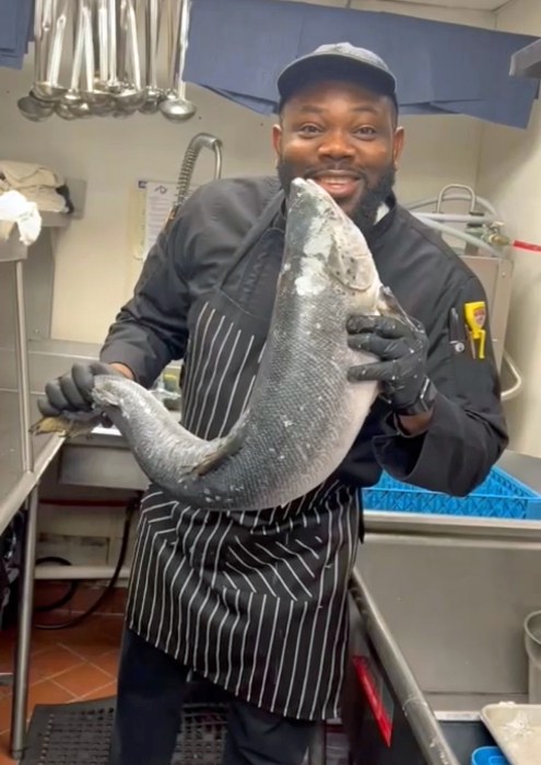 El chef Paul muestra con orgullo un gran pescado que está a punto de cocinar.