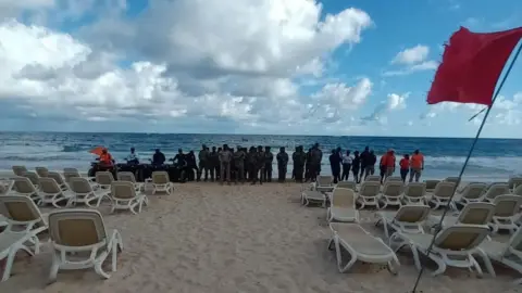 Defensa Civil Dominicana Funcionarios y uniformes en el ejército buscaron la playa, llena de sillas de playa, para Sodaksha Konki