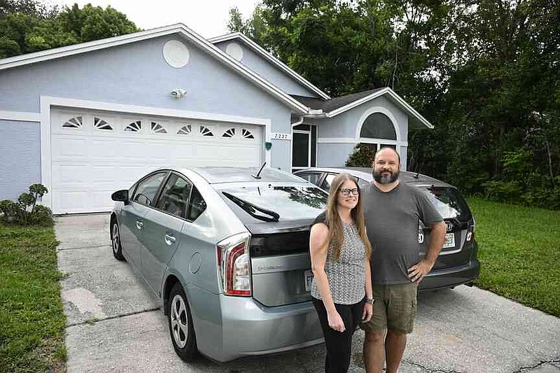 Headie y su esposo Patrick se paran en su menor, 1,600 pies cuadrados en casa y Toyota Pros, Izquierda 2013, y 2013 Honda Fit, jueves 24 de julio de 2025, Orlando, Florida (Photo/Fellan M. Ebin Hack)