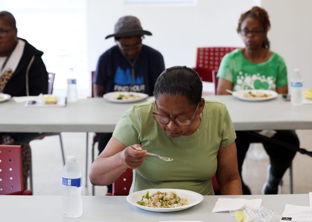 Cherryl Johnson y otros residentes del desarrollo de viviendas de Morsi Commons comen aves de corral y verduras hechas en una manifestación de cocina el 12 de agosto de 2025. (Tyranne Antonio James/Chicago Tribune)