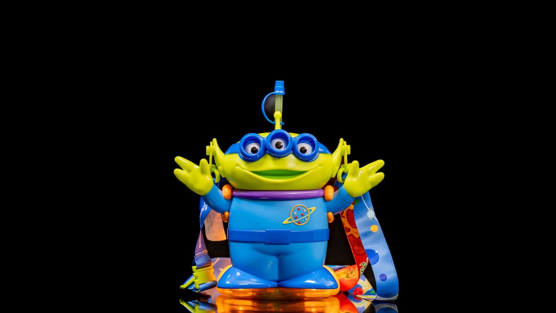 Un juguete alienígena azul y verde de tres años, como en cubos de palomitas de maíz en los parques de Disney, contra el fondo negro.
