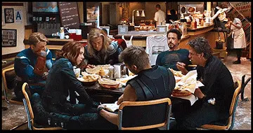 Un grupo de personajes de superhéroes sentados en la mesa, después de un programa de programa, comida y conversación.