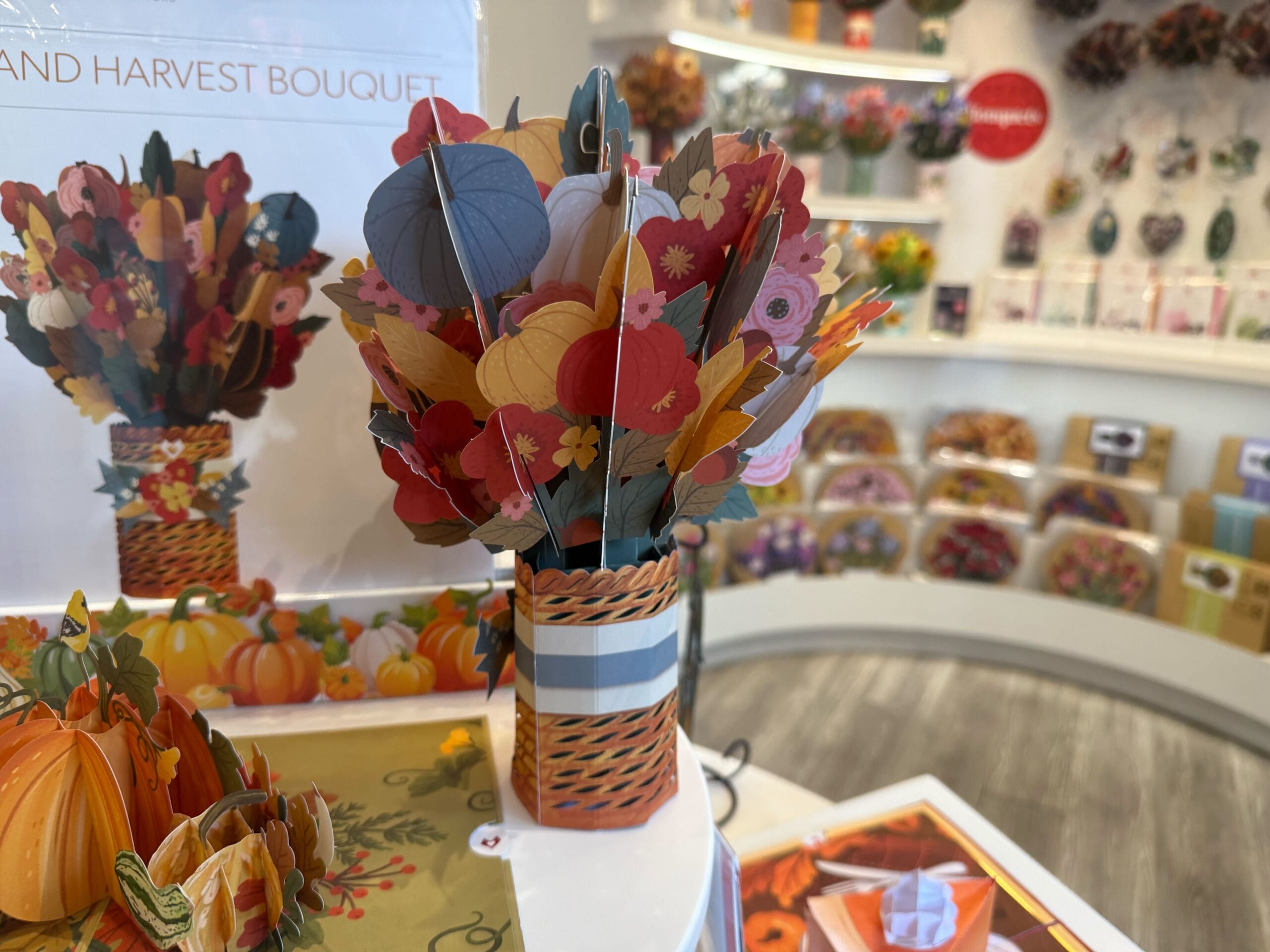 En una tienda de regalos, un ramo de papel de color con una tienda de regalos está en la exhibición con una tarjeta y una decoración en el fondo.