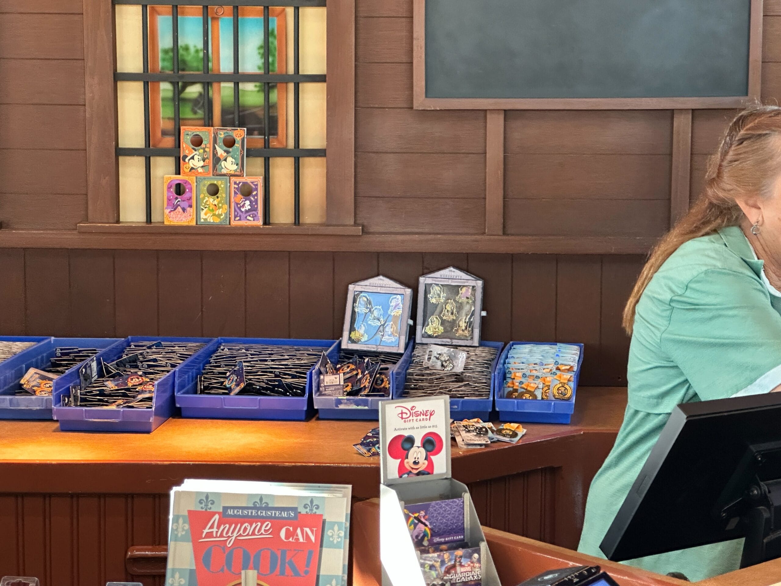 Disney World exhibe los pasadores de cumpleaños número 25 y Lionis, en el que un cajero a la derecha ayuda al cliente de comercio de PIN.