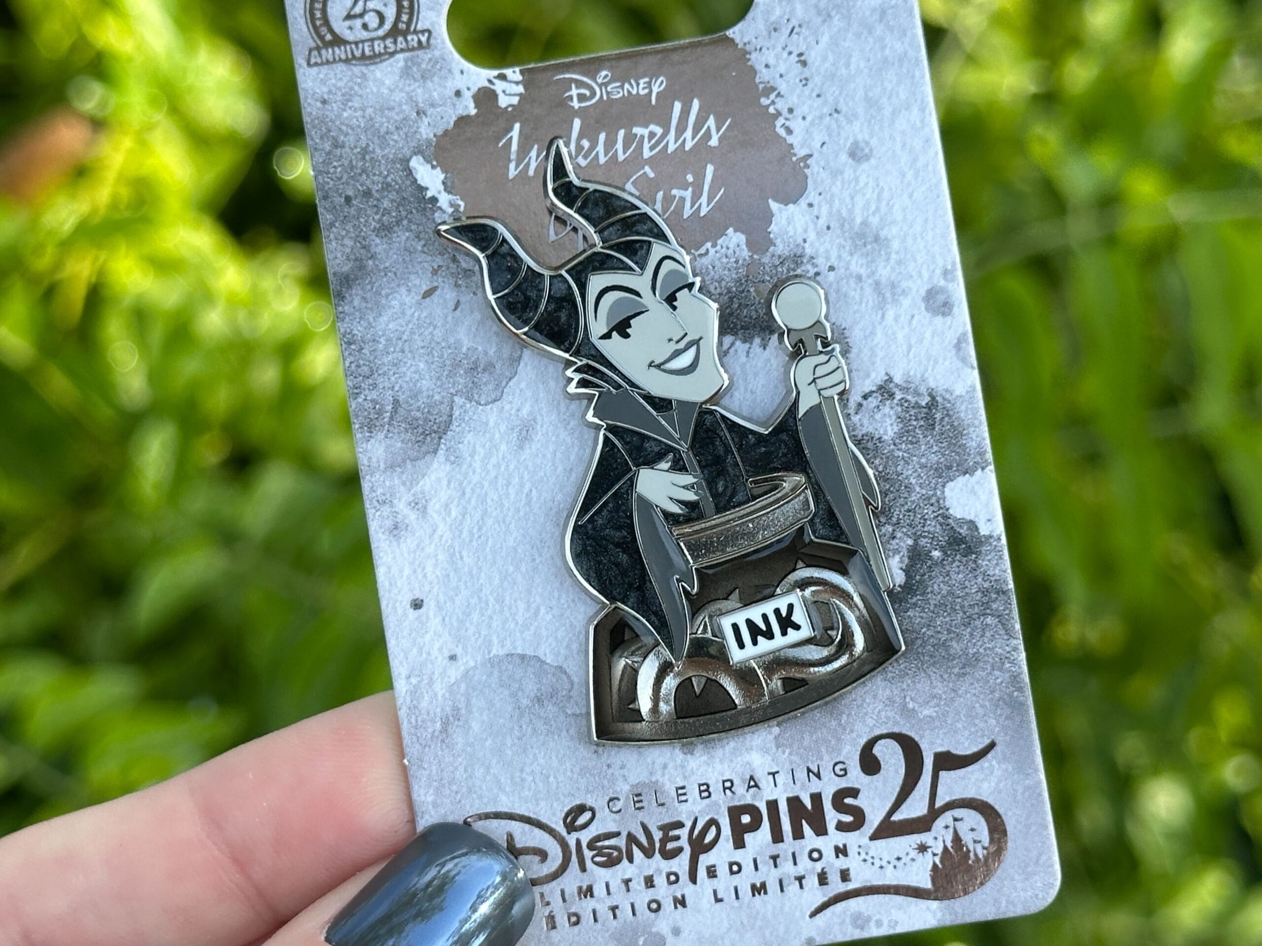 Los pasadores de cumpleaños número 25 en una mano son el pin de la niña de Disney Villers Melphstent.