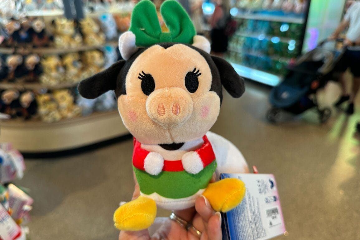 El peluche se asemeja a una vaca verde con un arco verde, en el que Walt Disney World se colocó en una tienda con estantes de lujos.