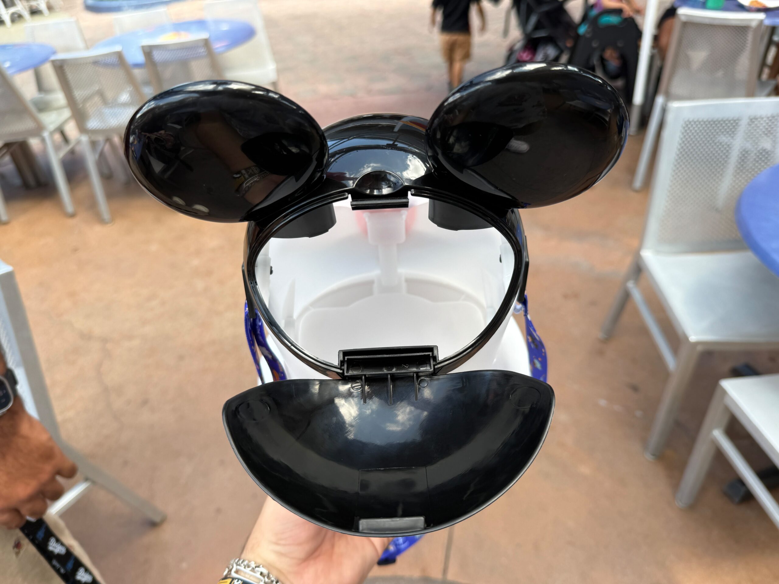 Una mano sostiene el cubo de palomitas de maíz Mickey Ghost Open en la zona de asientos al aire libre en Disneyland Resort para Halloween.