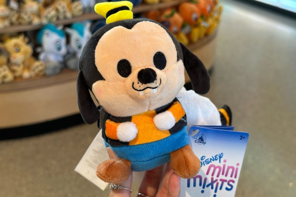 Una mano sostiene un juguete en una letra en una tienda Walt Disney World, con otra niebla pilosie en Disney.