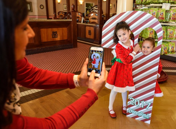 Abby McCrudden, izquierda, y su hermana, Ellie, posan con un bastón de caramelo gigante después de que su madre, Connie McCrudden, compra un bastón de caramelo recién hecho en Disneyland el viernes 1 de diciembre de 2017 en Anaheim. (Foto de Jeff Grchin, Registro del Condado de Orange/SCNG)