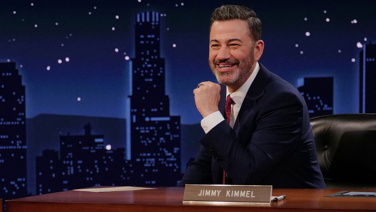 Jimmy Kimmel sentado en un escritorio en el set