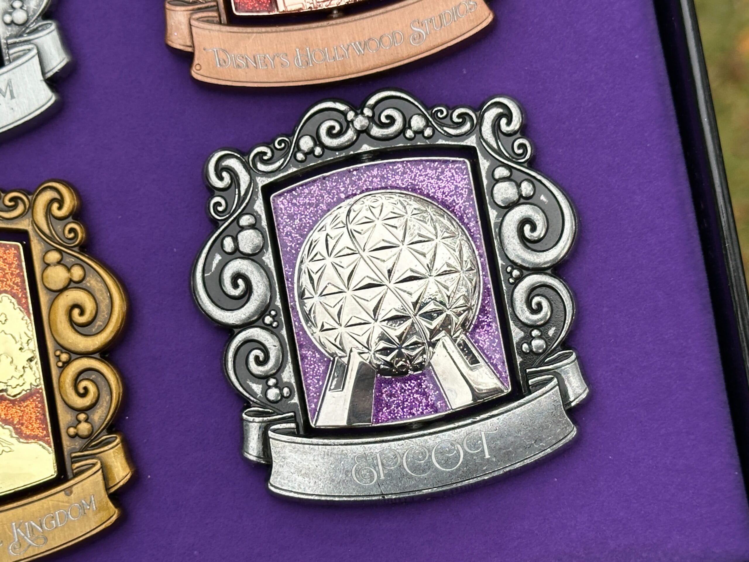 El pin de Epcot es plateado oscuro con una nave espacial Tierra sobre un fondo púrpura brillante. 