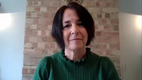 Andrea Brady, que tiene cabello gris oscuro, viste un jersey verde de punto trenzado y habla con BBC Breakfast a través de un enlace de zoom desde su casa.