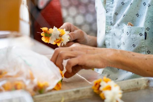 Sam C., propietario de MP Lei Shop, ensarta flores para hacer un lei en su tienda en Chinatown, el jueves 26 de febrero de 2026, en Honolulu. (Foto AP/Mengxin Lin)