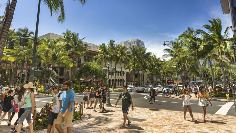 Los peatones caminan por las calles bordeadas de palmeras de Waikiki.