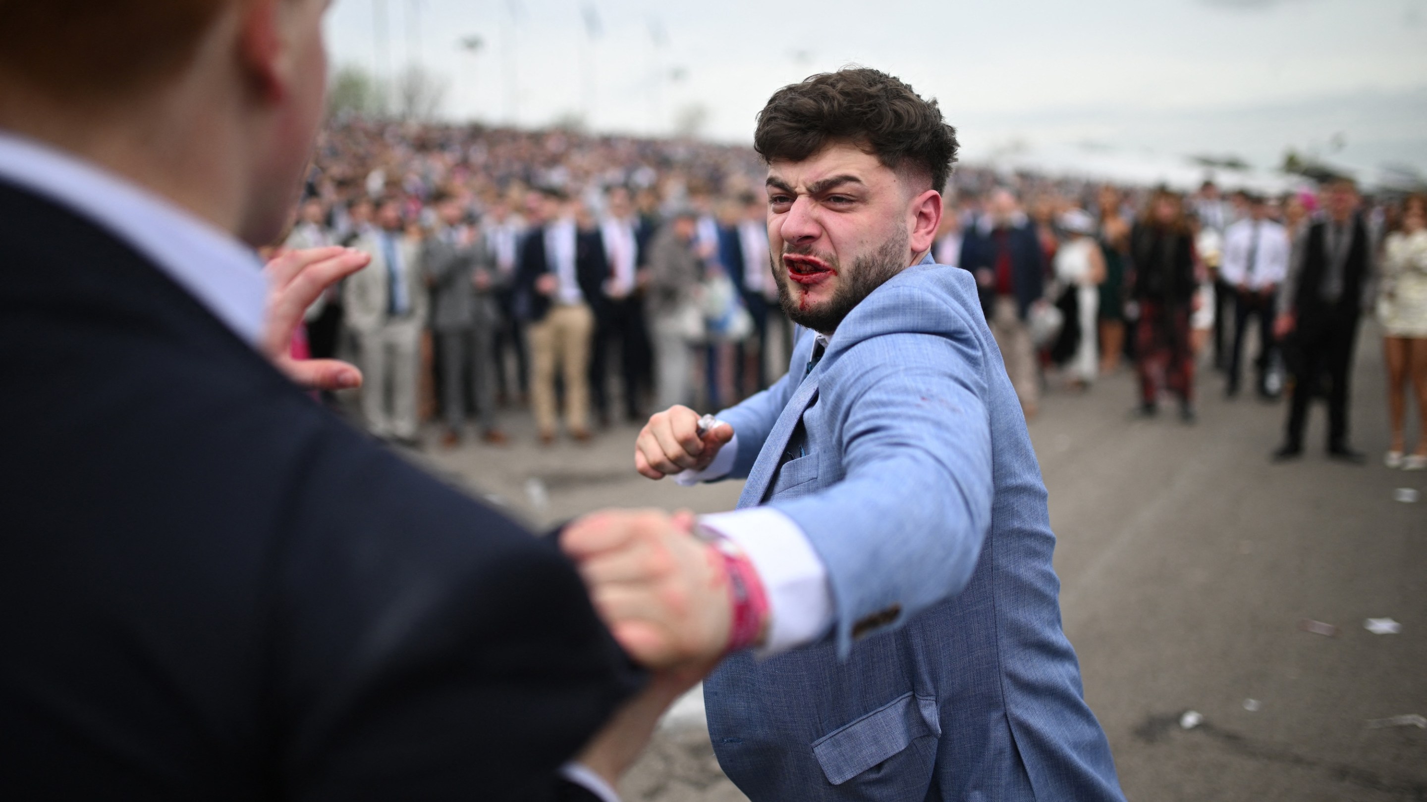 Los aficionados a las carreras luchan durante el segundo día del Gran Festival Nacional de Carreras de Caballos en el hipódromo de Aintree el 12 de abril de 2024 en Liverpool, noroeste de Inglaterra. (Foto de Ole Scharf/AFP)