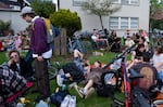 Una multitud se reúne en el césped en el perímetro exterior del parque. El evento atrae a cientos de personas cada año.