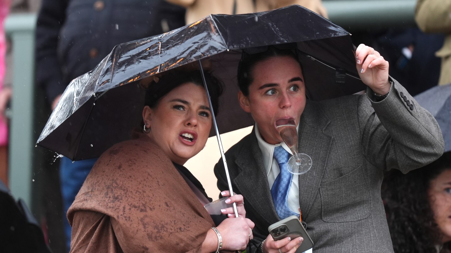 Los corredores intentan protegerse de la lluvia mientras ven el obstáculo de Turners Mersey Novices en el Gran Día Nacional del Gran Festival Nacional Randex 2026 en el hipódromo de Aintree.